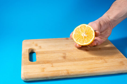 Hand Holding Lemon Isolated On Blue Pastel Background. 