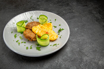 Delicious dinner with cutlet meal along with potatoes on a white plate on dark background
