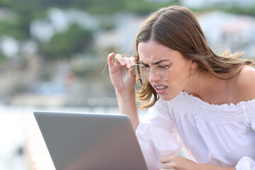 Woman with eyeglasses forcing sight using laptop
