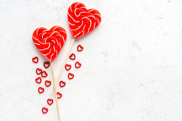 Heart shaped lollipop for Valentine's Day with decorative hearts on white stone background. Flat lay, top view, copy space.