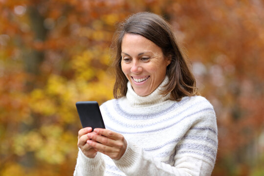 Happy Middle Age Woman Using Phone In Fall In A Park