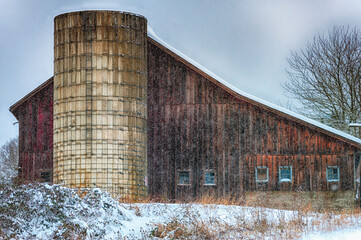 Fototapeta na wymiar Snow surrounds silo and barn in this countryside setting