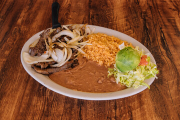 Beef topped with onions and rice with beans