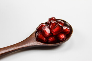 Close up. Macro. A wooden spoon with seeds in it. Wooden spoon with pomegranate seeds isolated on a white background. Fruit pomegranate. The concept of healthy eating.