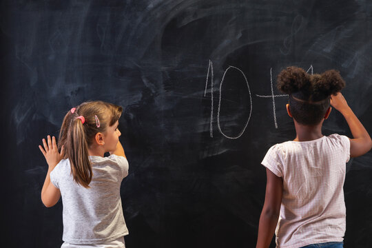 Two schoolgirls doing math on chalkboard in classroom