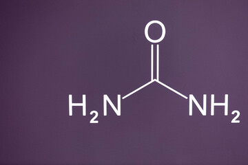 The formula of urea carbamide is written in white paint on a cement wall of purple color. Place for the inscription