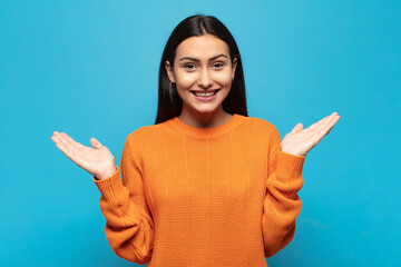 young hispanic woman feeling happy, excited, surprised or shocked, smiling and astonished at...