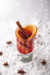 Mulled wine in glass glasses decorated with cinnamon sticks on snow. Christmas drink, New Year's punch. Vertical image