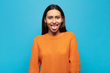 young hispanic woman with cheerful, carefree, rebellious attitude, joking and sticking tongue out,...