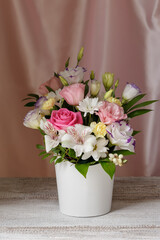 spring romantic bouquet of roses, daisies, lisianthus, chrysanthemums, unopened buds on light boards on a diagonal and a background of pink silk fabric.
