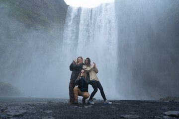 photo of happy tourist friends at the Skógafoss waterfall in Iceland