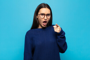 young hispanic woman pointing at camera with an angry aggressive expression looking like a furious,...
