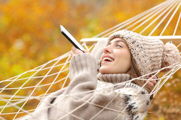 Happy lady on hammock dictating message on phone in fall