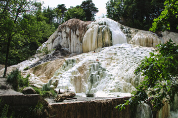 Fototapeta na wymiar natural outdoor thermal spring free to the public in the woods, large limestone conformations from where hot water comes out