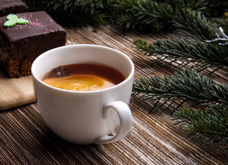 Obraz na płótnie Canvas chocolate glazed cupcake with shamrock and a cup of fruit tea next to a sprig of a Christmas tree