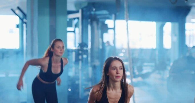 Determined pretty muscular three women doing jumpin exercises on boxes training their obliques working out in the gym. Female workout. Active lifestyle.