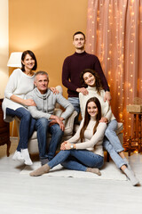 Christmas family photo for postcard. a large family. a group of people of different nationalities are sitting on a sofa in a decorated with New Year decorations. two generations of a family.