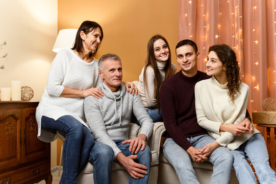 beautiful family is photographed in the New Year's decor while sitting on the couch. home comfort for christmas. new year bulbs. decoration for the new year. grandfather with baushka. children