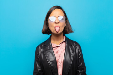 young hispanic woman feeling disgusted and irritated, sticking tongue out, disliking something...