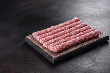 Fresh raw pork sausages with spices on a wooden cutting board