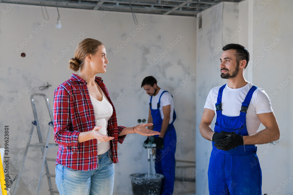 Wall mural A architect in a blue overalls shows the female client the progress of the repair