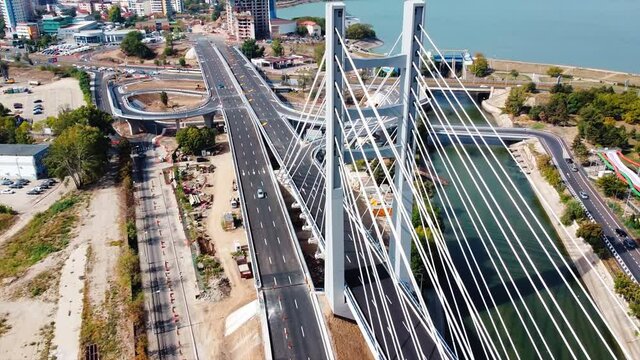 Ciurel passage, bridge over a river with moving cars, construction works, field and TV tower near it. Residential buildings on the background. View from the drone. Bucharest, Romania
