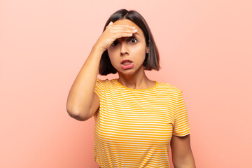 young hispanic woman panicking over a forgotten deadline, feeling stressed, having to cover up a...