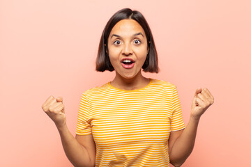 young hispanic woman celebrating an unbelievable success like a winner, looking excited and happy...