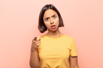 young hispanic woman pointing at camera with an angry aggressive expression looking like a furious,...