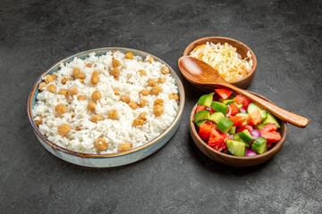 Close up view of seasoned split peas and rice sauerkraut and salad on dark background