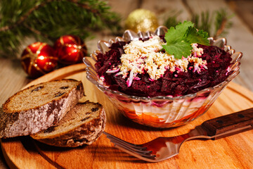 Traditional Russian herring under a fur coat in transparent plate with parsley. Rustic style. Christmas russian salad.