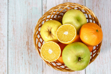 Top angle view on basket with fruit orange lemon and apples on table
