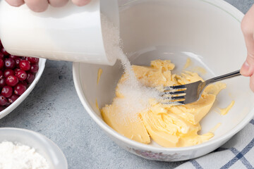 Making a dough for a sweet cranberry pie. Pouring sugar into butter