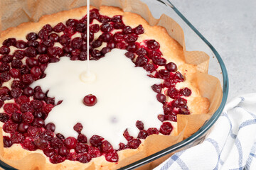 Homemade baking. Cooking sweet cranberry pie. Pouring cream