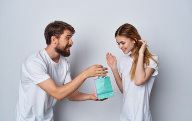 man with gift bags and women in white t-shirt emotions gray background