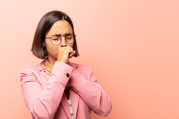 young hispanic woman feeling ill with a sore throat and flu symptoms, coughing with mouth covered