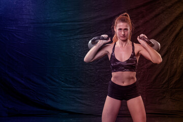 athletic girl in shorts and a top holds two weights in her hands