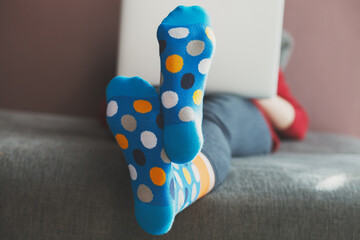 woman using laptop working at home, wearing funny warm colorful socks