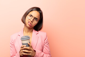 young hispanic woman feeling puzzled and confused, with a dumb, stunned expression looking at...
