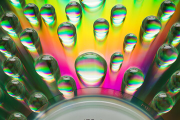 Rainbow spectrum water droplets are randomly located on the surface of the CD.