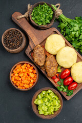 Delicious cutlets chopped vegetables a bunch of green and ketchup for on dark background