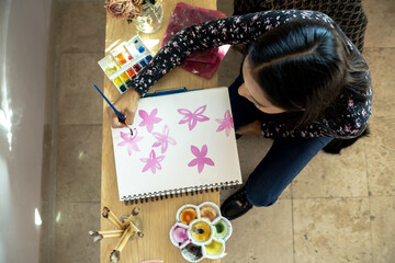 Fototapeta premium woman smiling and learning activity at home, during quarantine, overhead shot, painting with watercolor