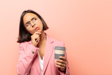young hispanic woman feeling thoughtful, wondering or imagining ideas, daydreaming and looking up...