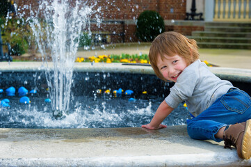 Boy playing with rubber ducks in fountain