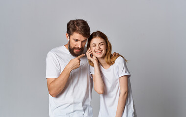 a man and a woman in white headphones stand side by side on a gray background in the same T-shirts