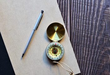 Aerial view. Compass on top of hardcover notebook and silver pen. Space for text or idea.