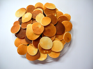 Plate with mini pancakes on a white background. Homemade delicious pastries.