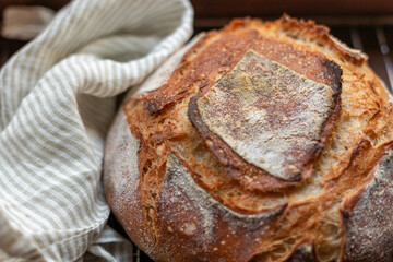 A loaf of freshly baked sourdough bread near a linen stripy towel