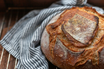 A loaf of freshly baked sourdough bread near a linen stripy towel