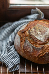 A loaf of freshly baked sourdough bread near a linen stripy towel